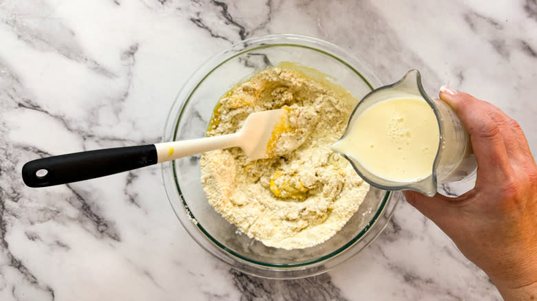 hand pouring buttermilk into bowl