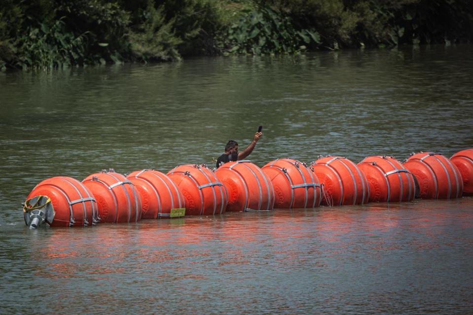 A man takes cellphone footage of buoys used in the Rio Grande to stop unauthorized border crossings on Thursday in Eagle Pass.