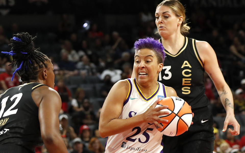 Los Angeles Sparks guard Layshia Clarendon (25) drives to the basket between Las Vegas Aces guard Chelsea Gray (12) and forward Cayla George (13) during the first half of a WNBA basketball game Saturday, Aug. 19, 2023, in Las Vegas. (Steve Marcus/Las Vegas Sun via AP)
