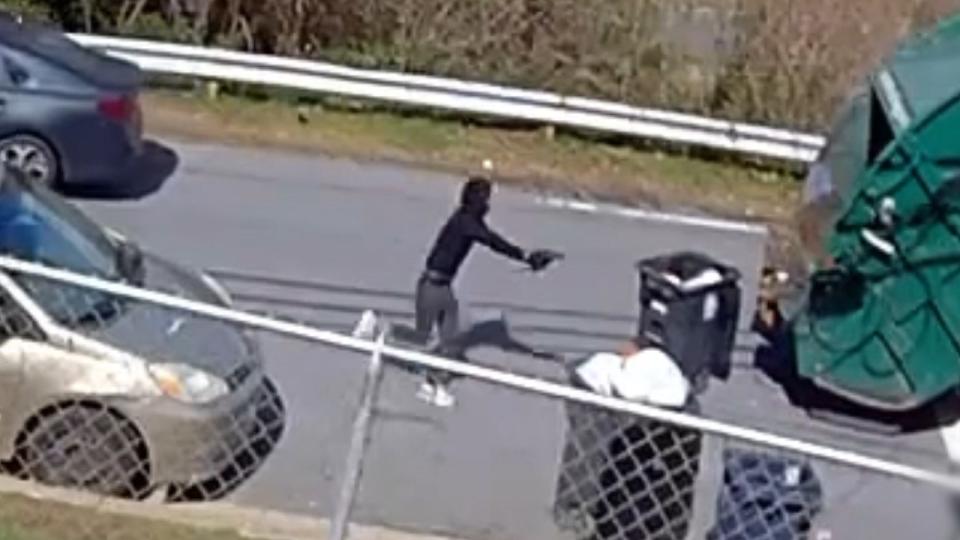 Person running in street with gun pointed out