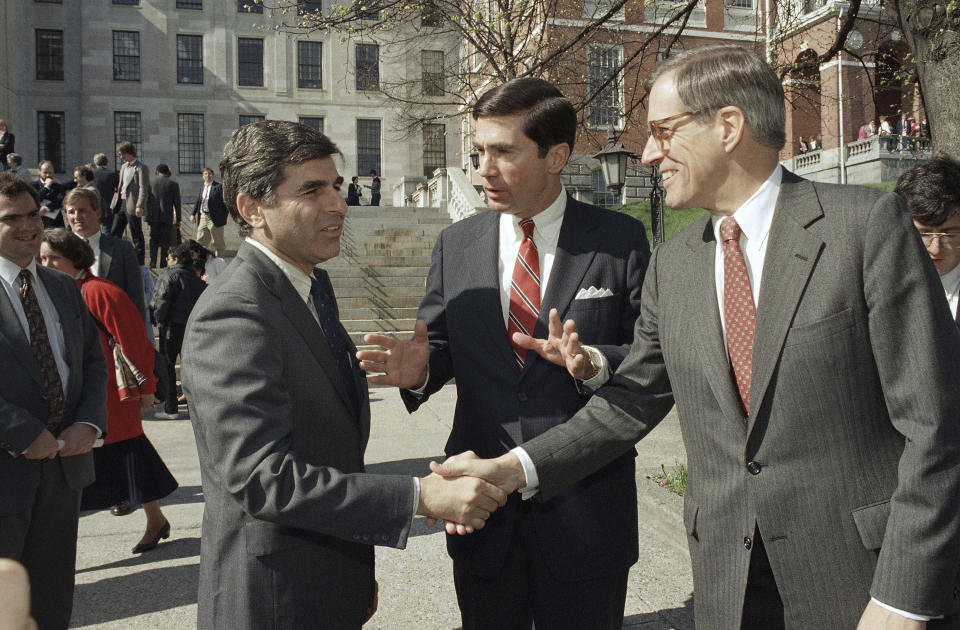 FILE - In this April 27, 1987, file photo, Massachusetts Governor Michael Dukakis, left, shakes the hands of former Delaware Governor Pierre Du Pont, right as former Virginia Governor Charles S. Robb looks on, after both men attended the Jobs for Bay State Grads program in Boston. Current and former Delaware politicians, family and friends of Pierre S. “Pete” du Pont IV remembered the late governor, U.S. House member and presidential candidate, for reviving the state’s economy, working across the partisan aisle and sharing a cheerful spirit. A memorial service, Friday, April 29, 2022 at a Wilmington theater came nearly a year after du Pont died in May 2021 at age 86 after a long illness. (AP Photo/Jim Shea, File)