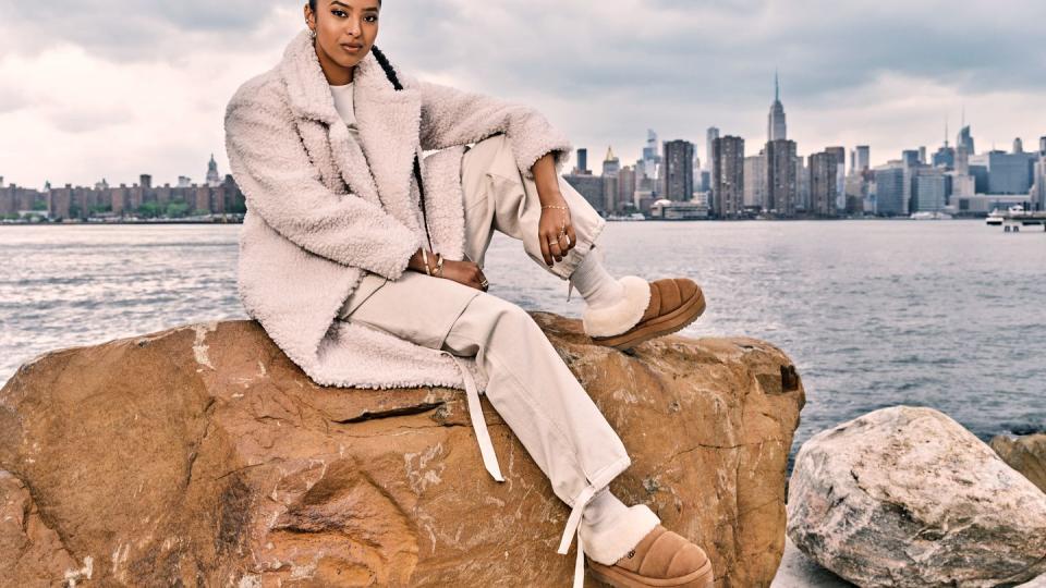 a person sitting on a rock by the water with a city in the background