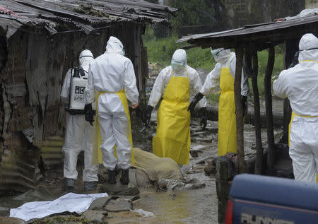 Health workers wearing protective clothing prepare to carry an abandoned dead body presenting with Ebola symptoms at Duwala market in Monrovia, August 17, 2014. REUTERS/2Tango