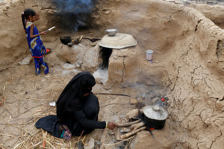 Afaf Hussein (L), 10, who is malnourished, and her sister cook a meal in their family's kitchen outside their house in the village of al-Jaraib, in the northwestern province of Hajjah, Yemen, February 19, 2019. Afaf, who now weighs around 11 kg and is described by her doctor as "skin and bones", has been left acutely malnourished by a limited diet during her growing years and suffering from hepatitis, likely caused by infected water. She left school two years ago because she got too weak. REUTERS/Khaled Abdullah