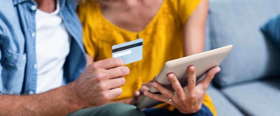 Couple sitting on sofa and doing online shopping on digital tablet