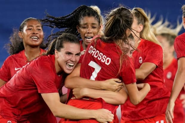 Vancouver's Julia Grosso is swarmed by teammates after scoring the decisive penalty kick in the shootout at the end of the Olympic soccer final in Tokyo.  (Fernando Vergara/The Associated Press - image credit)