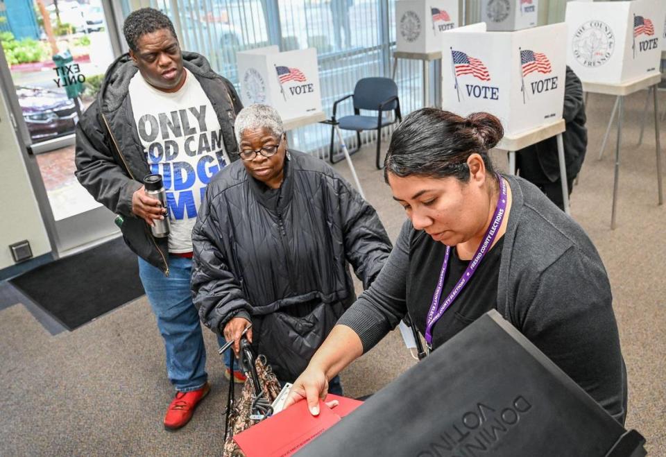 La trabajadora electoral Lori Loera, a la derecha, ayuda a los electores Shirley King y su hijo, LeeAndre Hannah, a registrar sus boletas electorales después de votar en persona en la oficina electoral del Condado de Fresno, en el centro de Fresno, antes de las elecciones generales del martes 7 de noviembre de 2022.