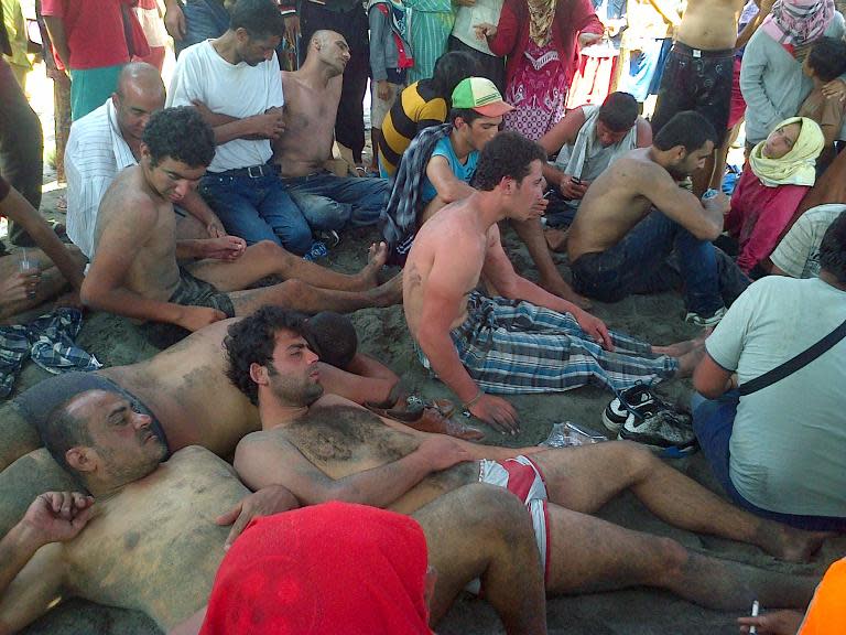 A group of asylum-seeker survivors rest on the beach in Cianjur on the Indonesian island of Java on September 27, 2013, after their boat sank