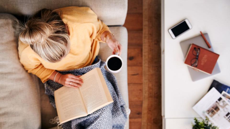 Woman reading a book while drinking coffee