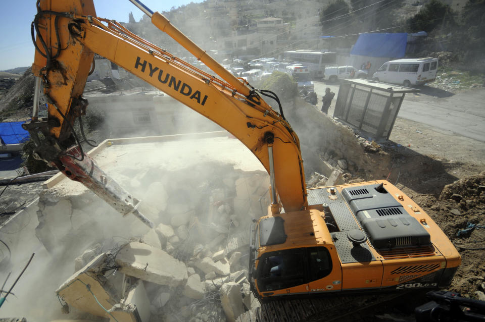 A bulldozer works on a Palestinian home demolished in East Jerusalem Wednesday, Feb. 5, 2014, Three Palestinian homes were demolished in the neighborhood, as the Israeli planners Wednesday gave final approval for 558 apartments in Jewish settlements in war-won east Jerusalem. (AP Photo/Mahmoud Illean)