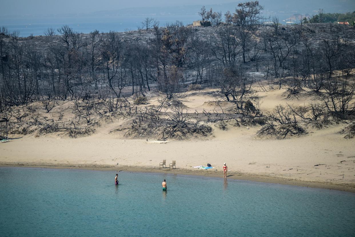 People swim in the sea in southern parts of Rhodes following large-scale wildfires. (Getty Images)