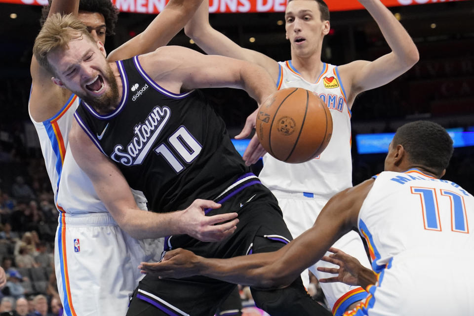 Oklahoma City Thunder guard Theo Maledon (11) knocks the ball away from Sacramento Kings' Domantas Sabonis (10) in the first half of an NBA basketball game Monday, Feb. 28, 2022, in Oklahoma City. (AP Photo/Sue Ogrocki)