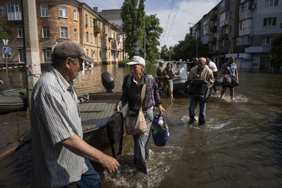 Alyona Shkrygalova carries her bags after evacuating from a flooded neighborhood on the left bank of the Dnipro river in Kherson, Ukraine, Friday, June 9, 2023. In Ukraine, the governor of the Kherson region, Oleksandr Prokudin, said Friday that water levels had decreased by about 20 centimeters (8 inches) overnight on the western bank of the Dnieper, which was inundated starting Tuesday after the breach of the Nova Kakhovka dam upstream. (AP Photo/Evgeniy Maloletka)