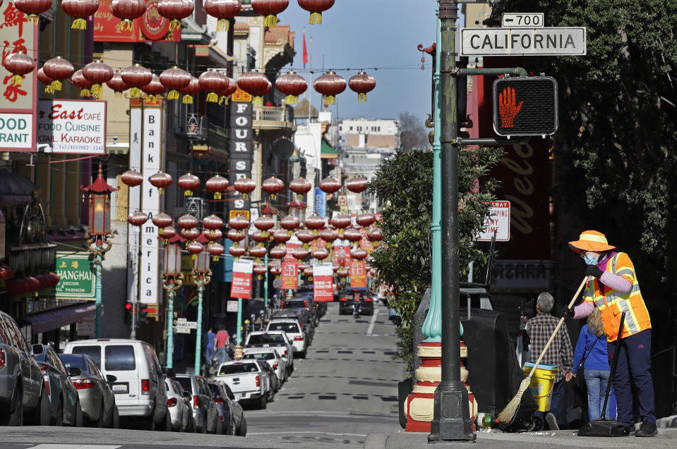 A masked worker cleans a street Friday, Jan. 31, 2020, in the Chinatown district in San Francisco. As China grapples with the growing coronavirus outbreak, Chinese people in California are encountering a cultural disconnect as they brace for a possible spread of the virus in their adopted homeland. (AP Photo/Ben Margot)