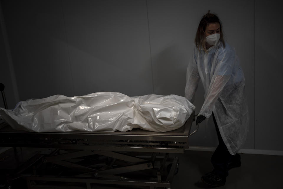 A funeral home worker moves a body in a morgue of an elderly person who died of COVID-19 in a nursing home in Barcelona, Spain, Tuesday, Nov. 17, 2020. Virus cases among the elderly are again on the rise across Europe, causing havoc and rising death tolls in nursing homes despite the lessons of a tragic spring. Authorities are in a race to save lives as they wait for crucial announcements on mass vaccinations. (AP Photo/Emilio Morenatti)