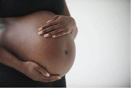 Midsection of pregnant Black woman holding belly - stock photo