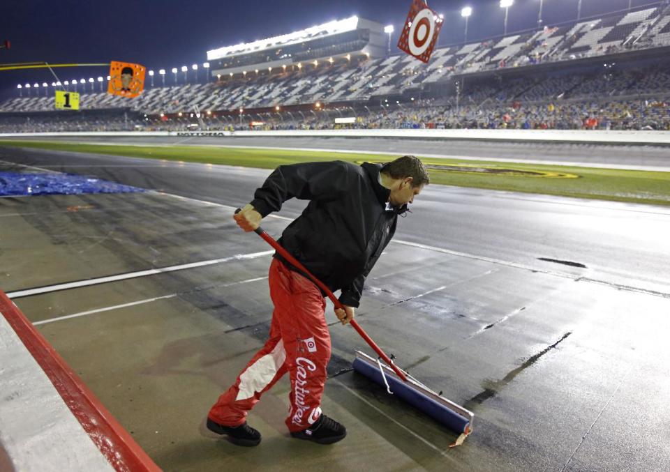 A crew member uses a squeegee to remove water from pit road during a rain delay in the NASCAR Daytona 500 Sprint Cup series auto race at Daytona International Speedway in Daytona Beach, Fla., Sunday, Feb. 23, 2014. (AP Photo/Terry Renna)