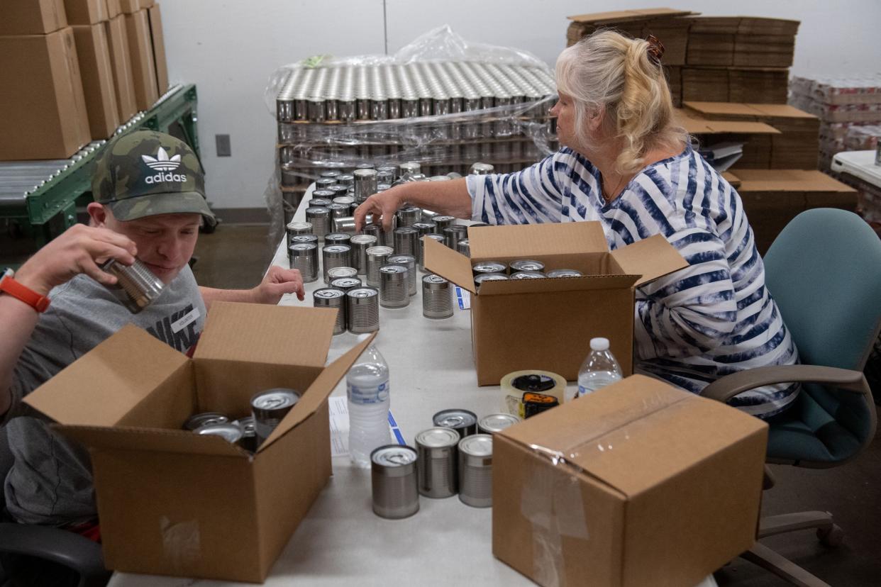 Volunteers Joseph Wiman, left, and Donna York, right, place handmade labels on cans at the Tri-State Food Bank in Evansville, Ind., Wednesday morning, June 22, 2022. Wiman enjoys volunteering and helps three days a week.