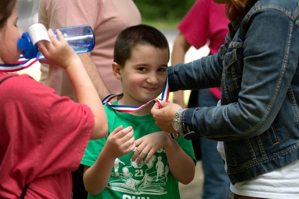 William Goppoeld receives a medal for participating in orienteering with his grandma as a part of Bucks County Senior Games at Tyler State Park in Newtown on Tuesday, June 14, 2022.