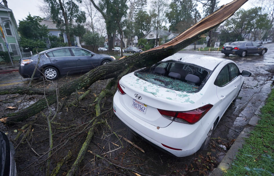 A car sustained damage when a tree limb fell on it during an overnight storm that swept through Sacramento, Calif., Wednesday, Jan. 27, 2021. (AP Photo/Rich Pedroncelli)