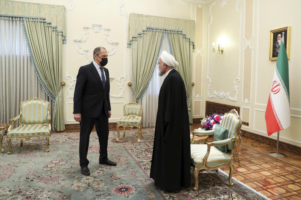 In this photo released by the official website of the office of the Iranian Presidency, Iranian President Hassan Rouhani, right, welcomes Russian Foreign Minister Sergey Lavrov, for their meeting in Tehran, Iran, Tuesday, April 13, 2021. (Iranian Presidency Office via AP)