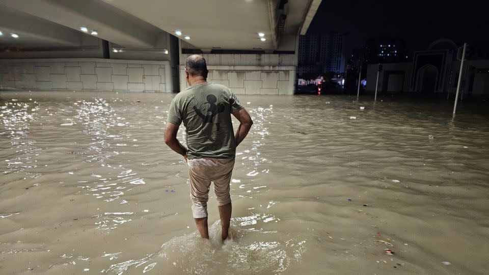 People wade through a submerged street under a bridge after heavy rain in the United Arab Emirates on Tuesday. - Stringer/Anadolu/Getty Images