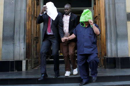 A Kenyan police officer escorts suspects, after fake currency was seized in a personal safety deposit box at the Queensway branch of Barclays Bank Kenya, in downtown Nairobi, Kenya, March 19, 2019. REUTERS/Njeri Mwangi