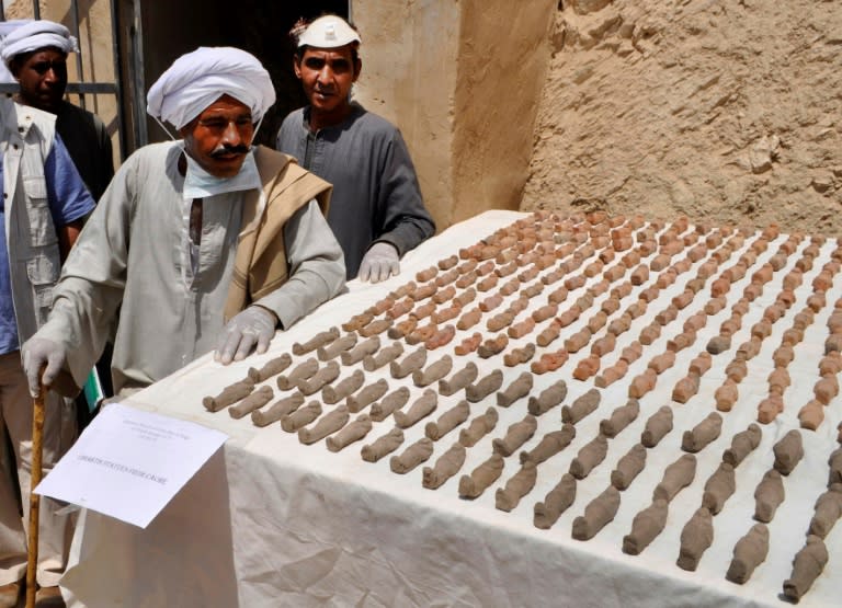 Members of an Egyptian archaeological team stand near artifacts, known as Ushabtis, discovered in a 3,500-year-old tomb in the Draa Abul Nagaa necropolis, near the southern city of Luxor, on April 18, 2017