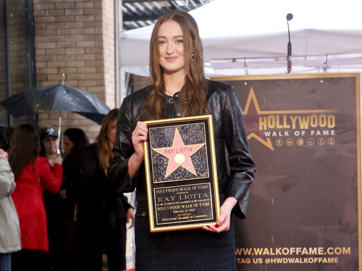 Karsen Liotta smiles and holds a plaque at father Ray Liotta's Hollywood Walk of Fame ceremony.