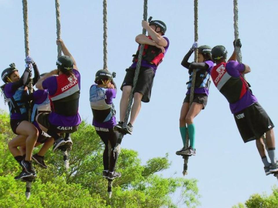 Players from MTV's The Challenge hanging on to ropes midair.