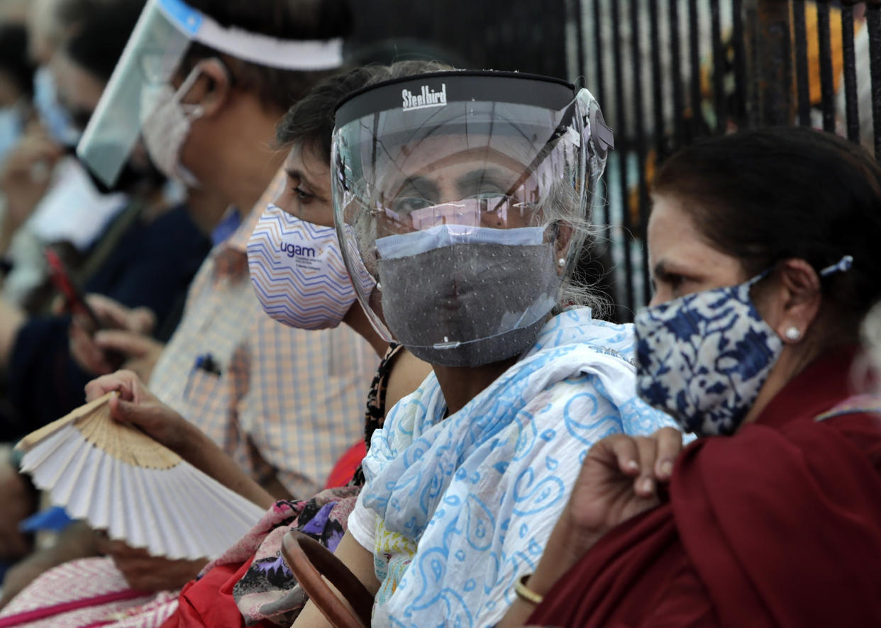 People wearing face shields and masks as a precaution against the coronavirus as they wait to receive COVID-19 vaccine in Mumbai, India, Thursday, April 29, 2021. India set another global record in new virus cases Thursday, as millions of people in one state cast votes despite rising infections and the country geared up to open its vaccination rollout to all adults amid snags. (AP Photo/Rajanish Kakade)