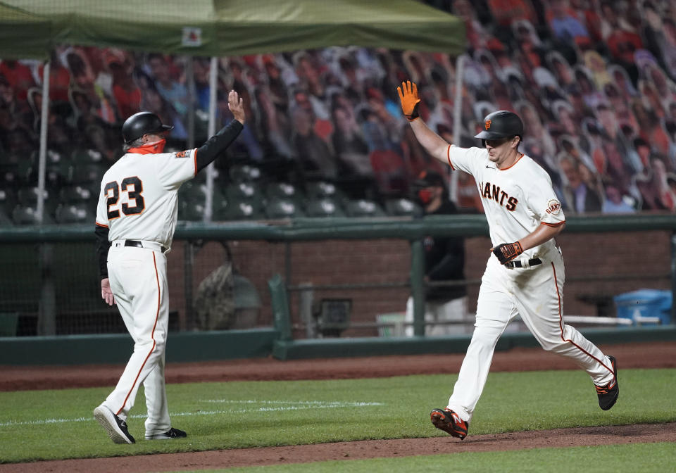 San Francisco Giants third base coach Ron Wotus, left, virtually high-fives Alex Dickerson, who runs the bases after hitting a solo home run against the Seattle Mariners during the third inning of a baseball game Tuesday, Sept. 8, 2020, in San Francisco. (AP Photo/Tony Avelar)