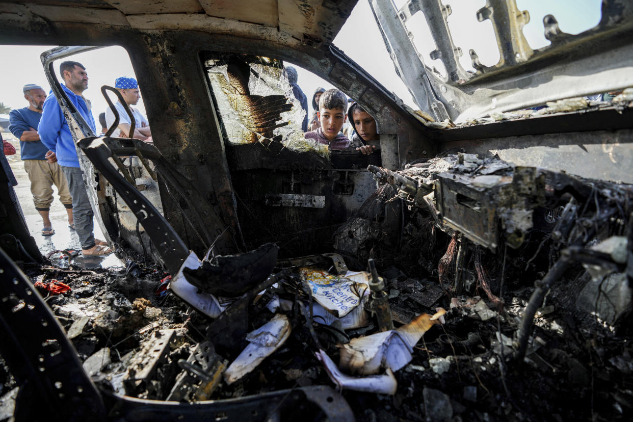 People inspect the site on Tuesday where World Central Kitchen workers were killed in Deir al-Balah, Gaza Strip.