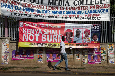 A man walks past a banner calling for prevention of violence during the primaries elections in the city of Kisumu, Kenya April 20, 2017. REUTERS/Baz Ratner