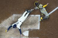 Milwaukee Brewers' Brice Turang slides safely past San Diego Padres catcher Kyle Higashioka during the eighth inning of a baseball game Wednesday, April 17, 2024, in Milwaukee. (AP Photo/Morry Gash)