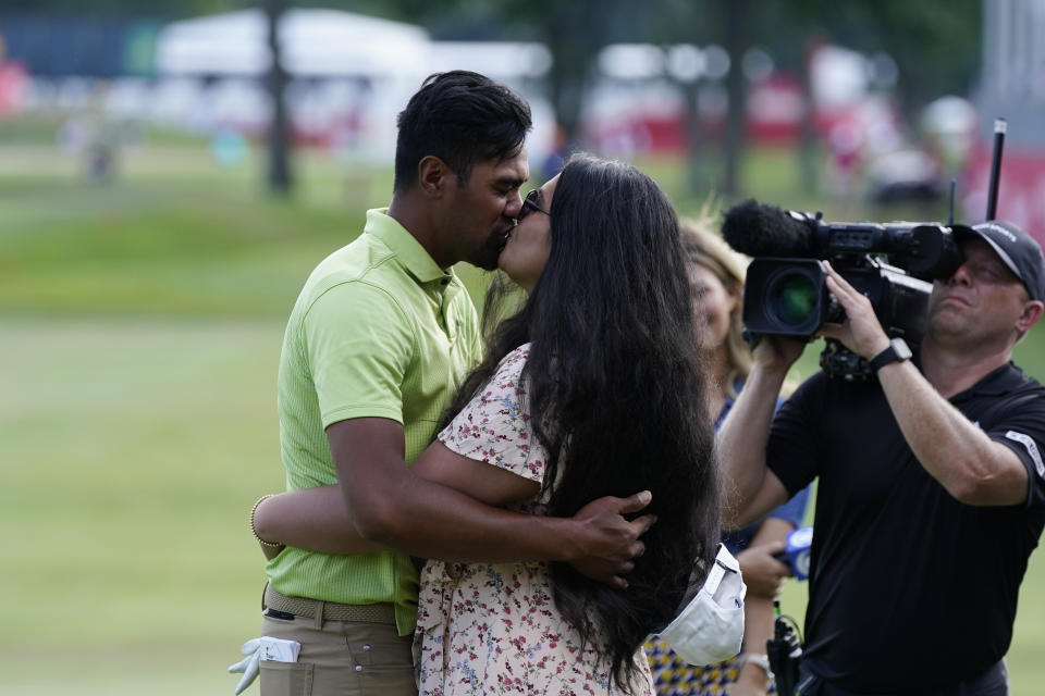 Tony Finau kisses his wife Alayna on the 18th green after winning the Rocket Mortgage Classic golf tournament, Sunday, July 31, 2022, in Detroit. (AP Photo/Carlos Osorio)