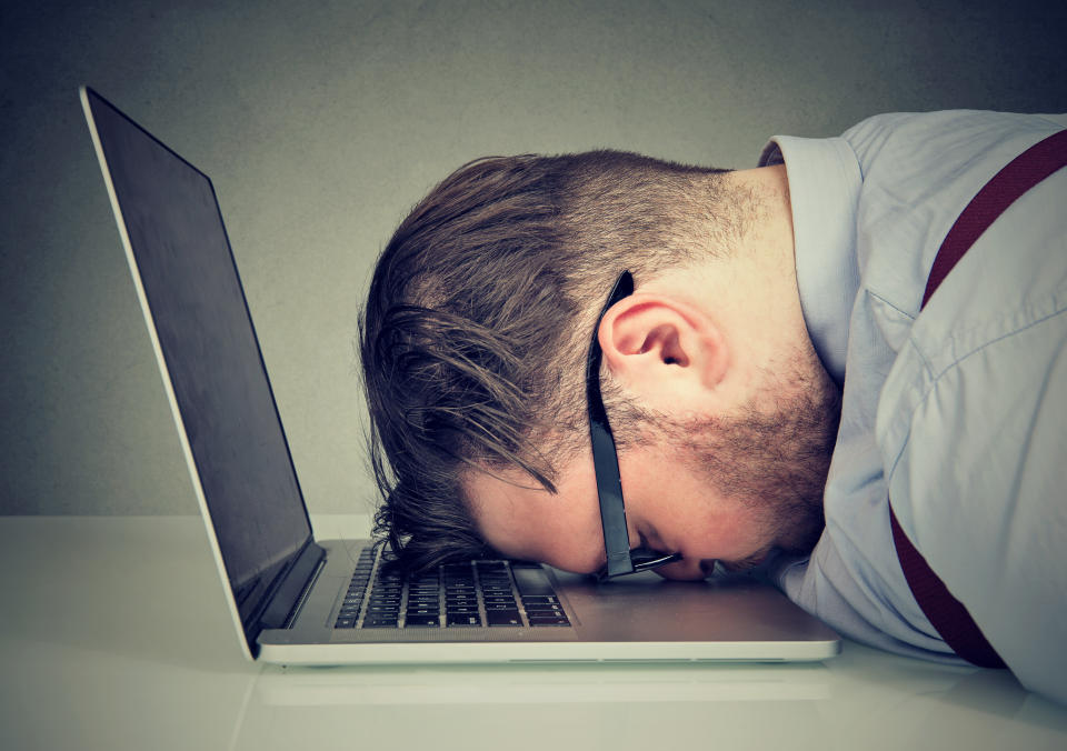 Man resting head on laptop.