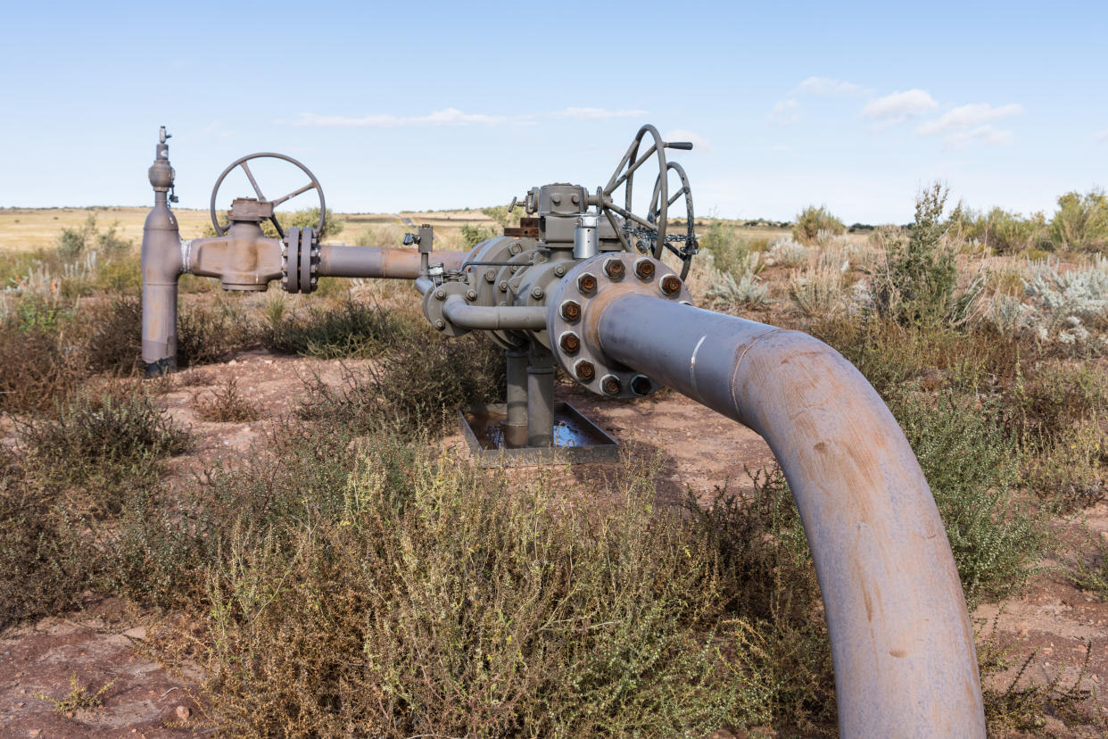 A crude oil collection pipeline is surrounded by scrubby brush in an oil field in Utah.