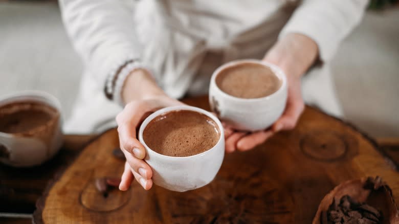 person holding two mugs of hot chocolate