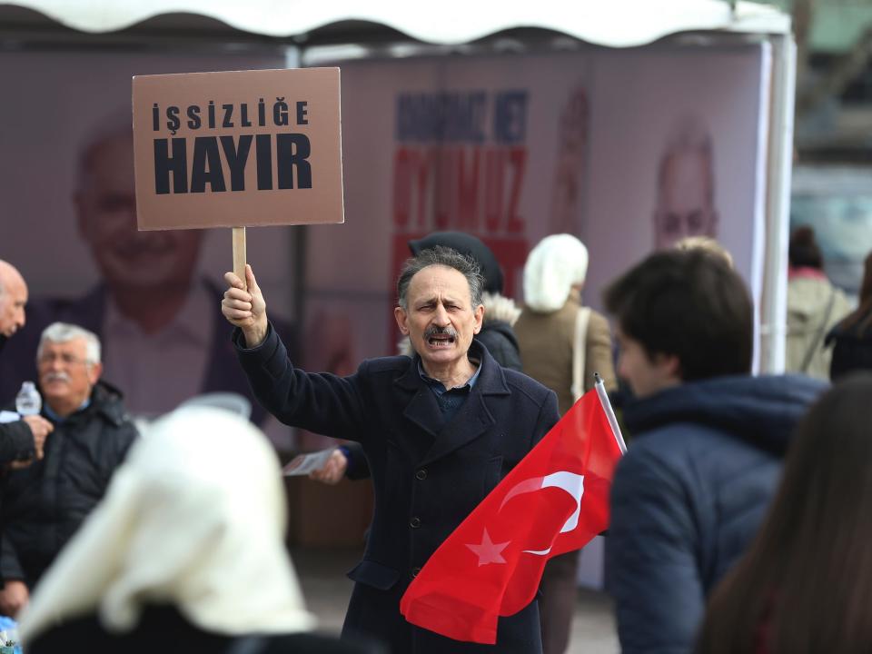 A Turkish man supporting the 'NO' vote for the upcoming referendum, holds a Turkish flag and a placard, reading in Turkish: 'No to unemployment', in Istanbul, Wednesday, March 15, 2017. Turkey is set to hold a referendum on April 16, 2017, on switching to a presidential system _ a move critics fear will concentrate too many powers in the hands of President Recep Tayyip Erdogan. (