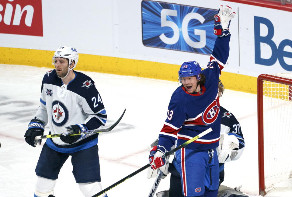 Montreal Canadiens' Tyler Toffoli, right, celebrates his goal past Winnipeg Jets goaltender Connor Hellebuyck, back right, as defenseman Derek Forbort looks on during second-period NHL hockey game action in Montreal, Thursday, March 4, 2021. (Paul Chiasson/The Canadian Press via AP)