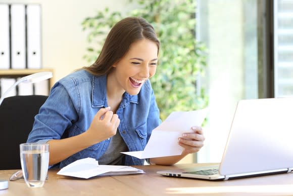 Woman reading letter at laptop and smiling