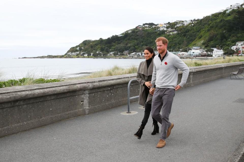 Prince Harry and Meghan Markle hold hands as they walk along Lyall Bay.