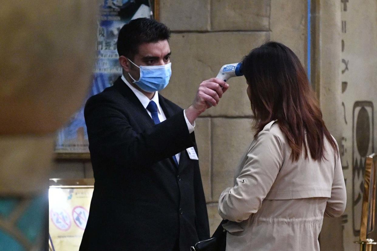 A staff member checks the temperature of a guest entering the casino of the New Orient Landmark hotel in Macau: AFP via Getty Images