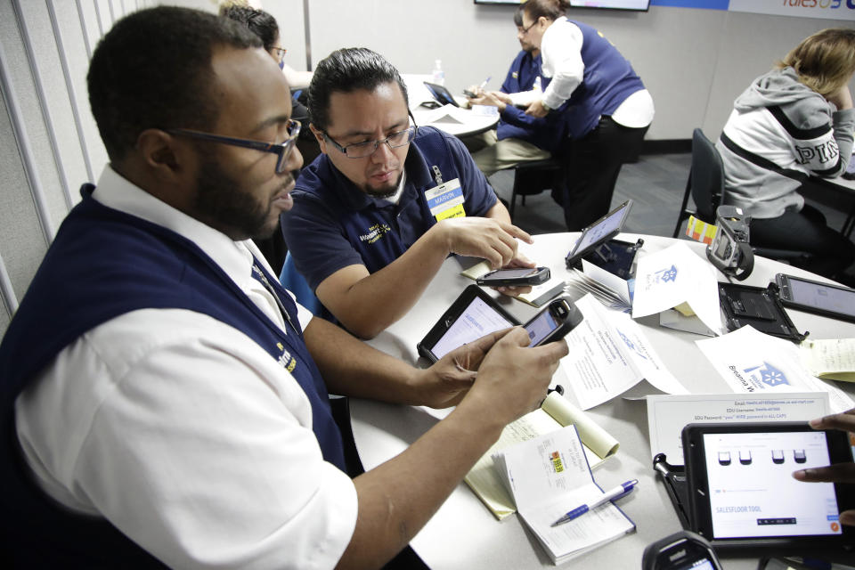 In this Thursday, Nov. 9, 2017, photo, Walmart employees Kenneth White, left, and Marvin Toc work together using an inventory app while participating in a class at the Walmart Academy at the store in North Bergen, N.J. The retail industry is being radically reshaped by technology and nobody feels that disruption more starkly than the 16 million Americans working as shelf stockers, salespeople and cashiers. (AP Photo/Julio Cortez)