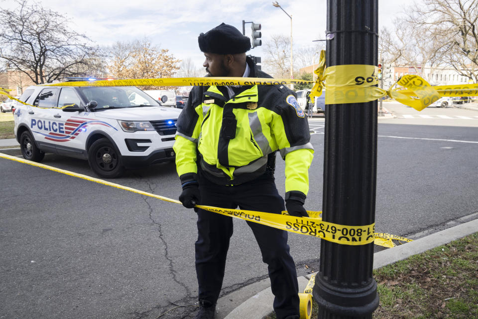 A Washington Metropolitan Police officer, puts yellow tape around the Potomac Avenue Metro Station in Southeast Washington, Wednesday, Feb. 1, 2023. An armed man shot three people, killing one, Wednesday in a morning rampage that started on a city bus and ended in a Metro tunnel after passengers attacked and disarmed him. (AP Photo/Manuel Balce Ceneta)