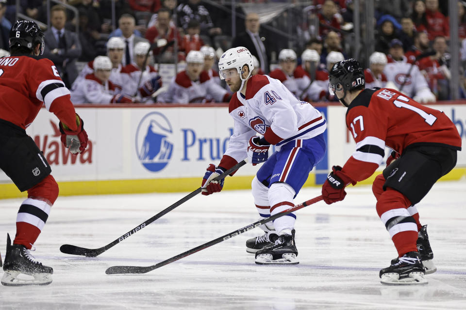 Montreal Canadiens right wing Joel Armia (40) looks to pass the puck from between New Jersey Devils' Simon Nemec (17) and John Marino during the first period of an NHL hockey game Wednesday, Jan. 17, 2024, in Newark, N.J. (AP Photo/Adam Hunger)