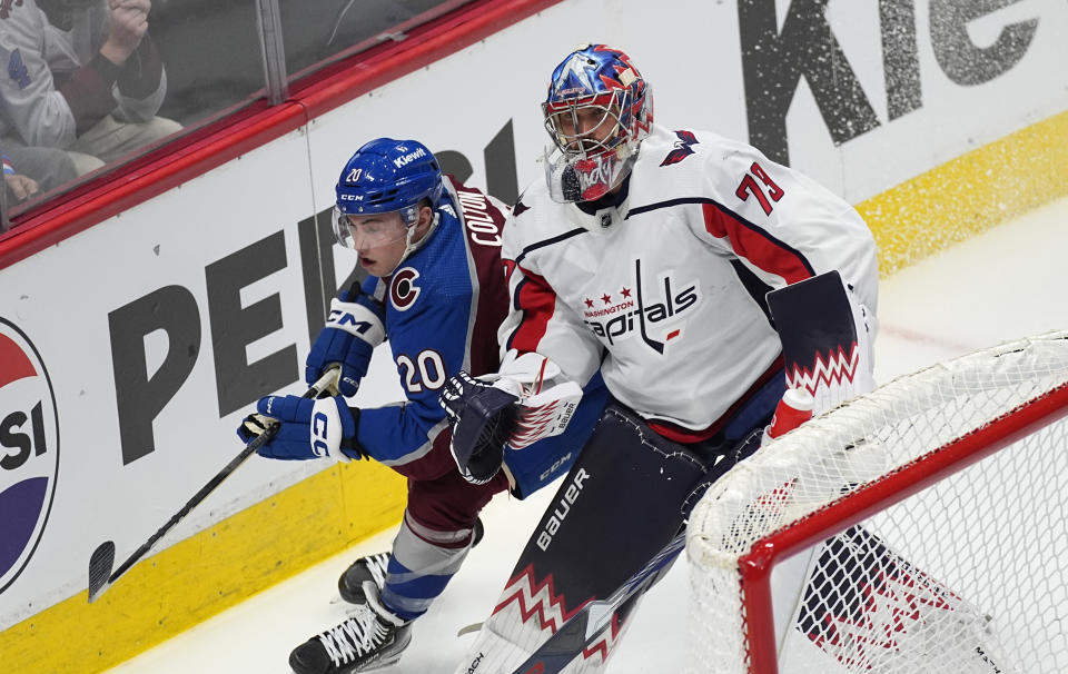 Washington Capitals goaltender Charlie Lindgren, right, clears the puck as Colorado Avalanche center Ross Colton defends in the first period of an NHL hockey game Wednesday, Jan. 24, 2024, in Denver. (AP Photo/David Zalubowski)