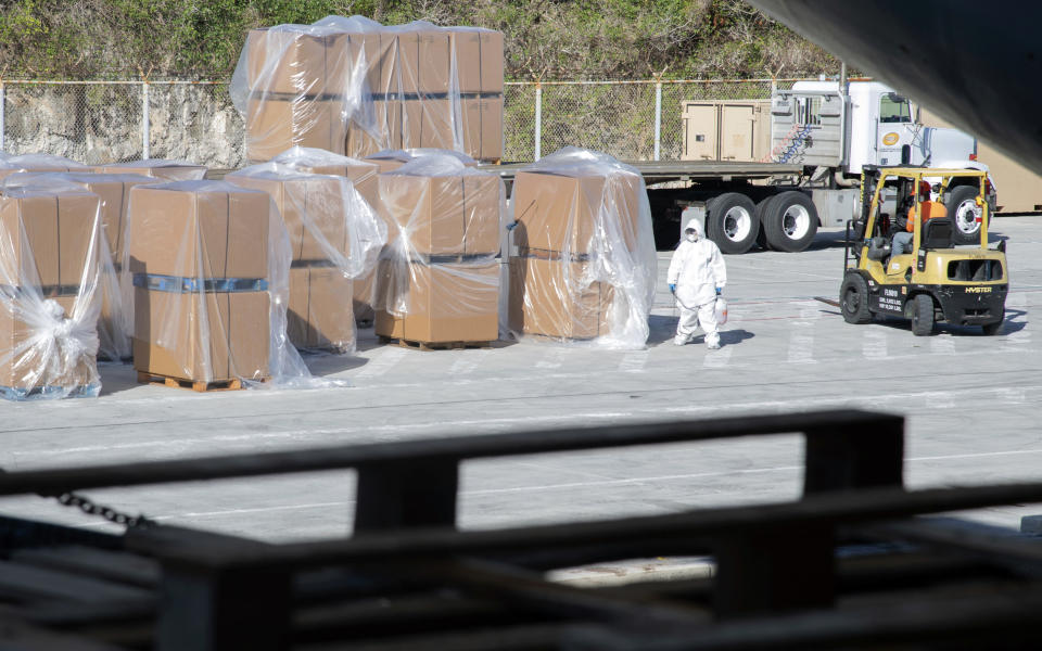 In this image provided by the U.S. Navy, a U.S. service member disinfects boxes of mail with sanitizer before the boxes are loaded onto the aircraft carrier USS Theodore Roosevelt (CVN 71) on April 13, 2020. The Navy’s top admiral will soon decide the fate of the ship captain who was fired after pleading for his superiors to move faster to safeguard his coronavirus-infected crew on the USS Theodore Roosevelt. (Mass Communication Specialist Seaman Kaylianna Genier/U.S. Navy via AP)