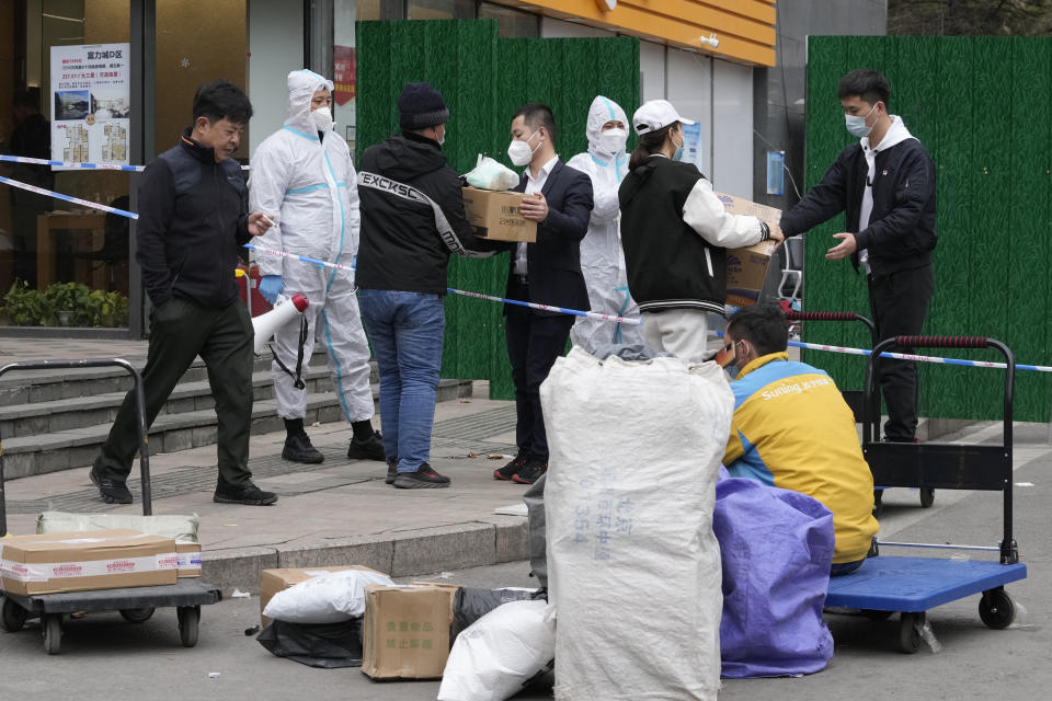 Workers collect deliveries for a lockdown community on Sunday, March 13, 2022, in Beijing. The number of new coronavirus cases in an outbreak in China's northeast tripled Sunday and authorities tightened control on access to Shanghai in the east, suspending bus service to the city of 24 million and requiring a virus test for anyone who wants to enter. (AP Photo/Ng Han Guan)